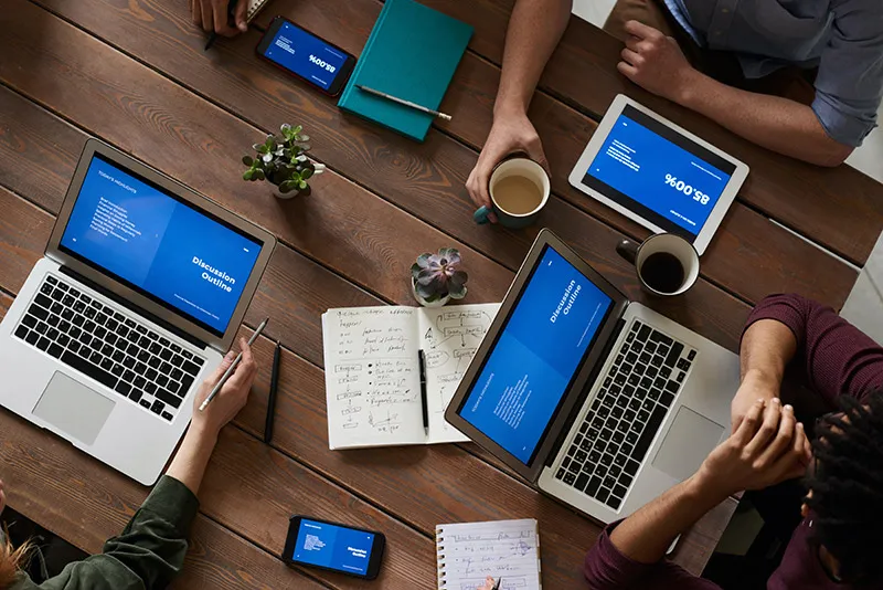 A team reviewing campaign performance figures across laptops and tablets